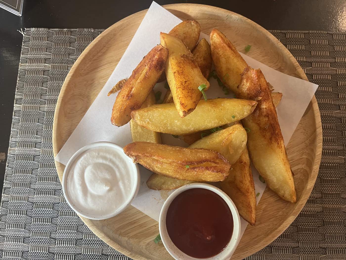 A plate of home-cooked potato wedges with two dips, photographed from above — our own photograph.