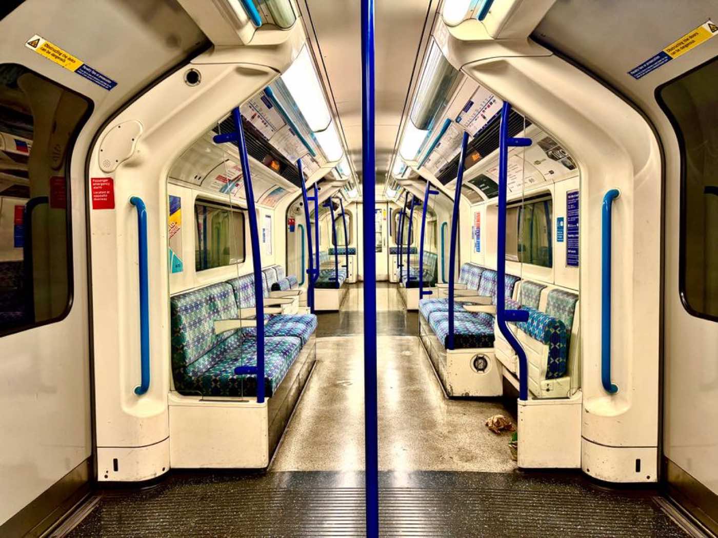The interior of an empty London Underground carriage, seen down the aisle.