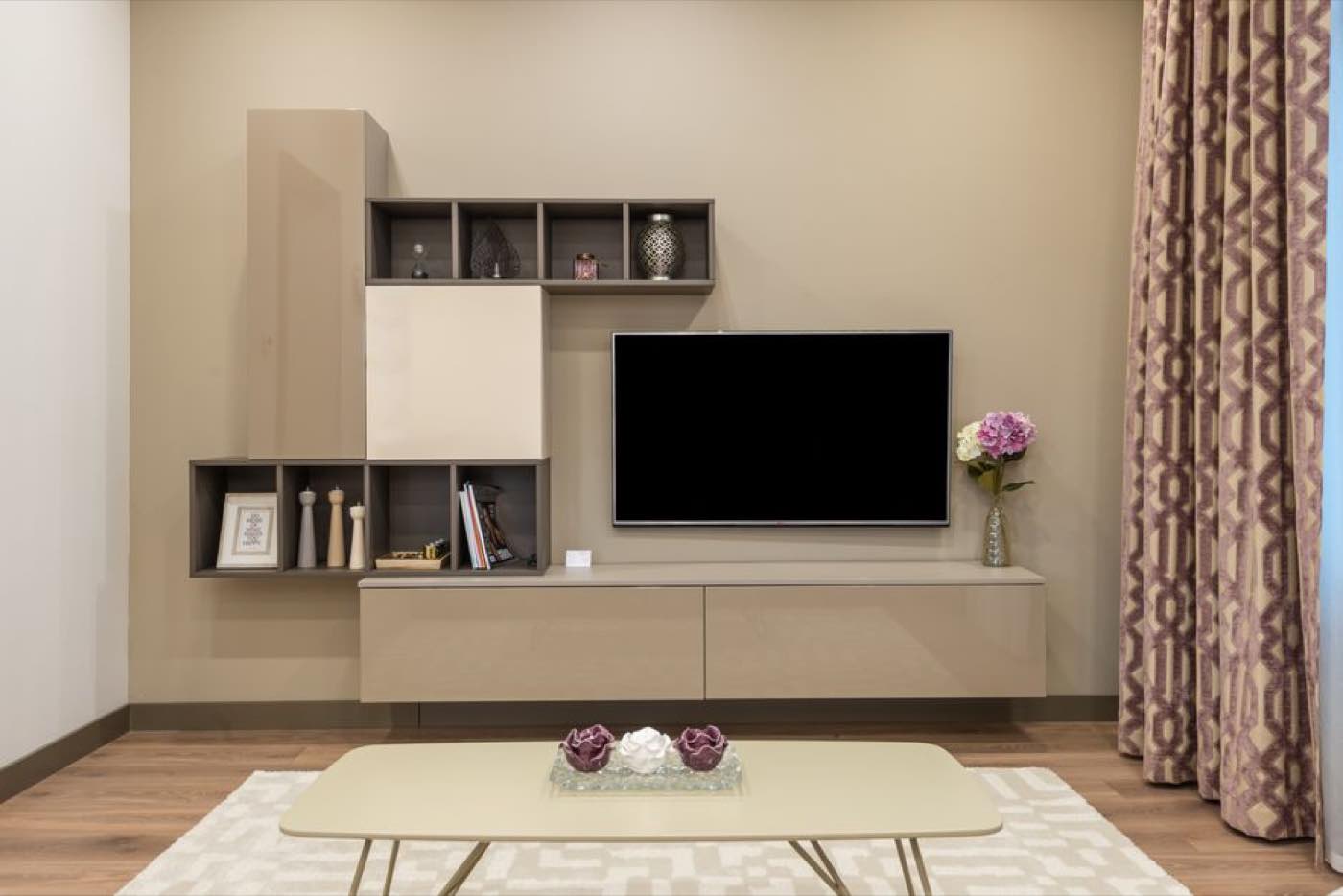 A living room with a wall-mounted television, low cabinet and coffee table.