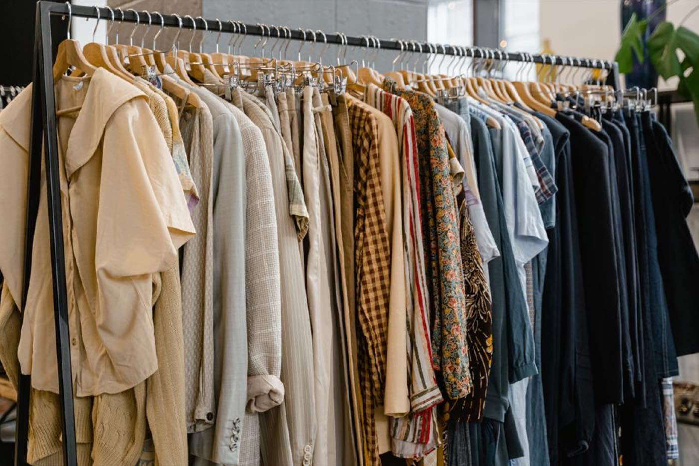 A clothes rail hung with neutral-toned shirts, knitwear and jackets.